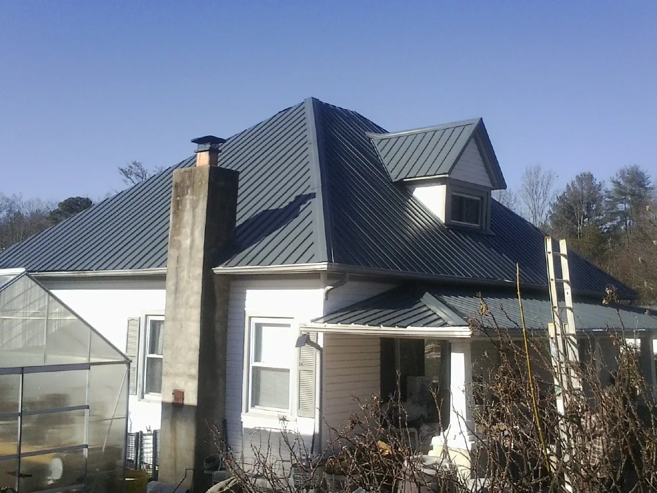 Dark blue standing seam metal roof on a white farmhouse with dormer — Slate & Tile Roof Repair by Roofing Brothers in Mays Landing
