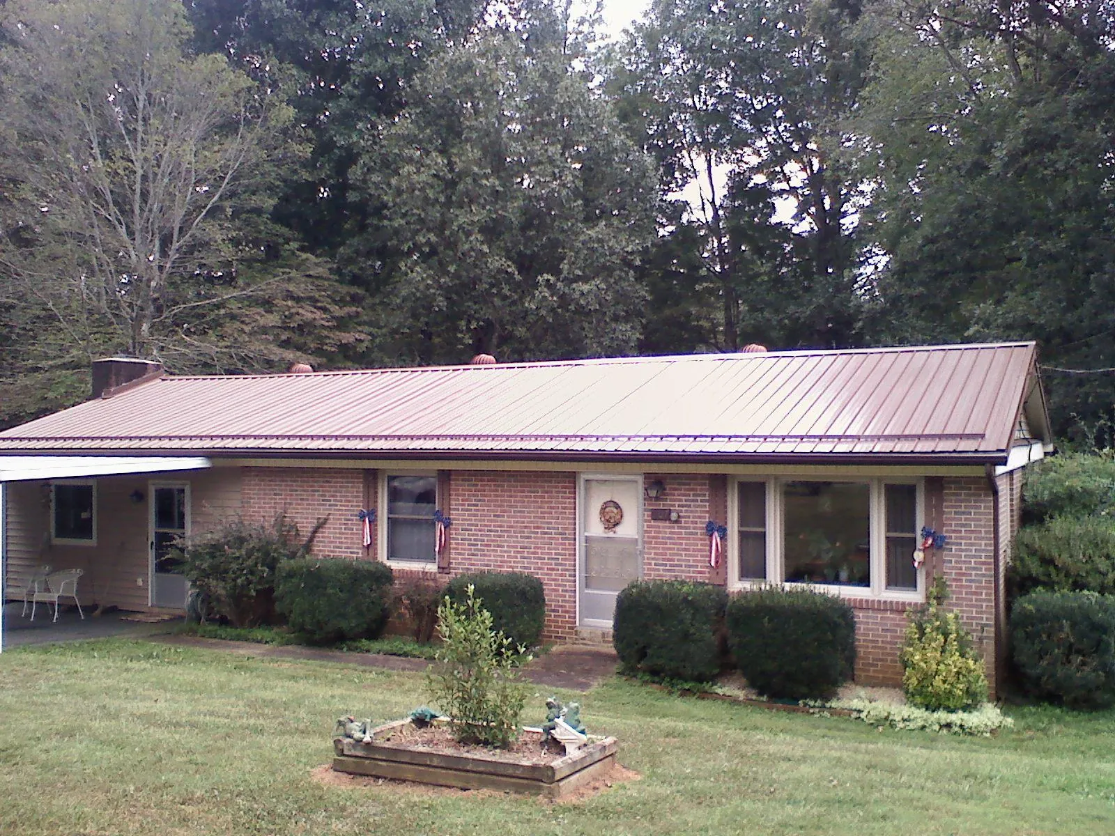 Bronze metal roof on a brick ranch home with a carport in Mays Landing