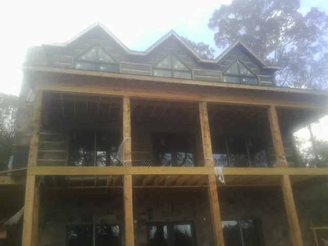 Dormers and porch framing on a large log home under construction — Roof Coating work by our crew in Mays Landing