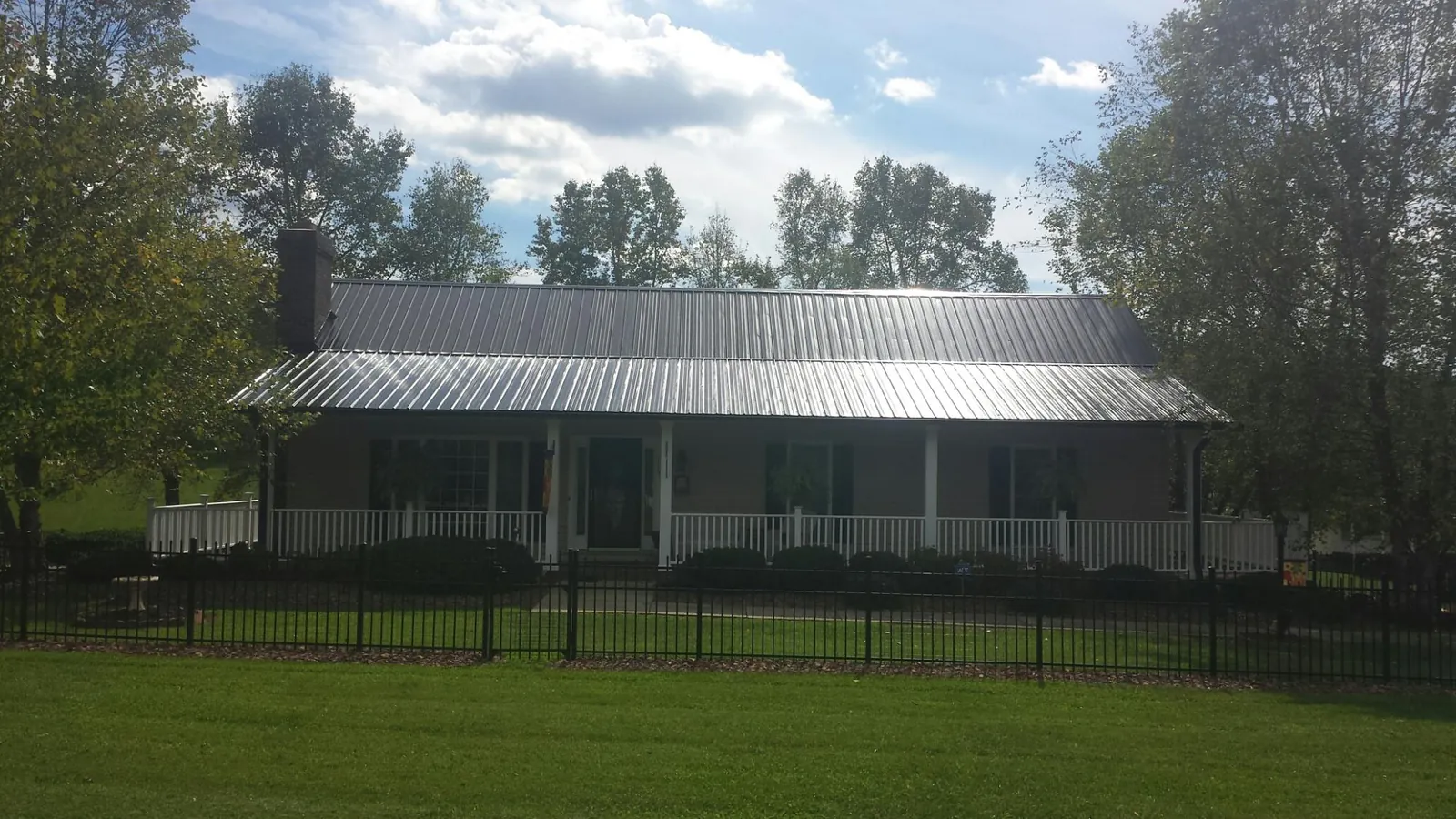 Gray metal roof on a brick ranch with a full width front porch — Gutter Guard Installation work by our crew in Mays Landing