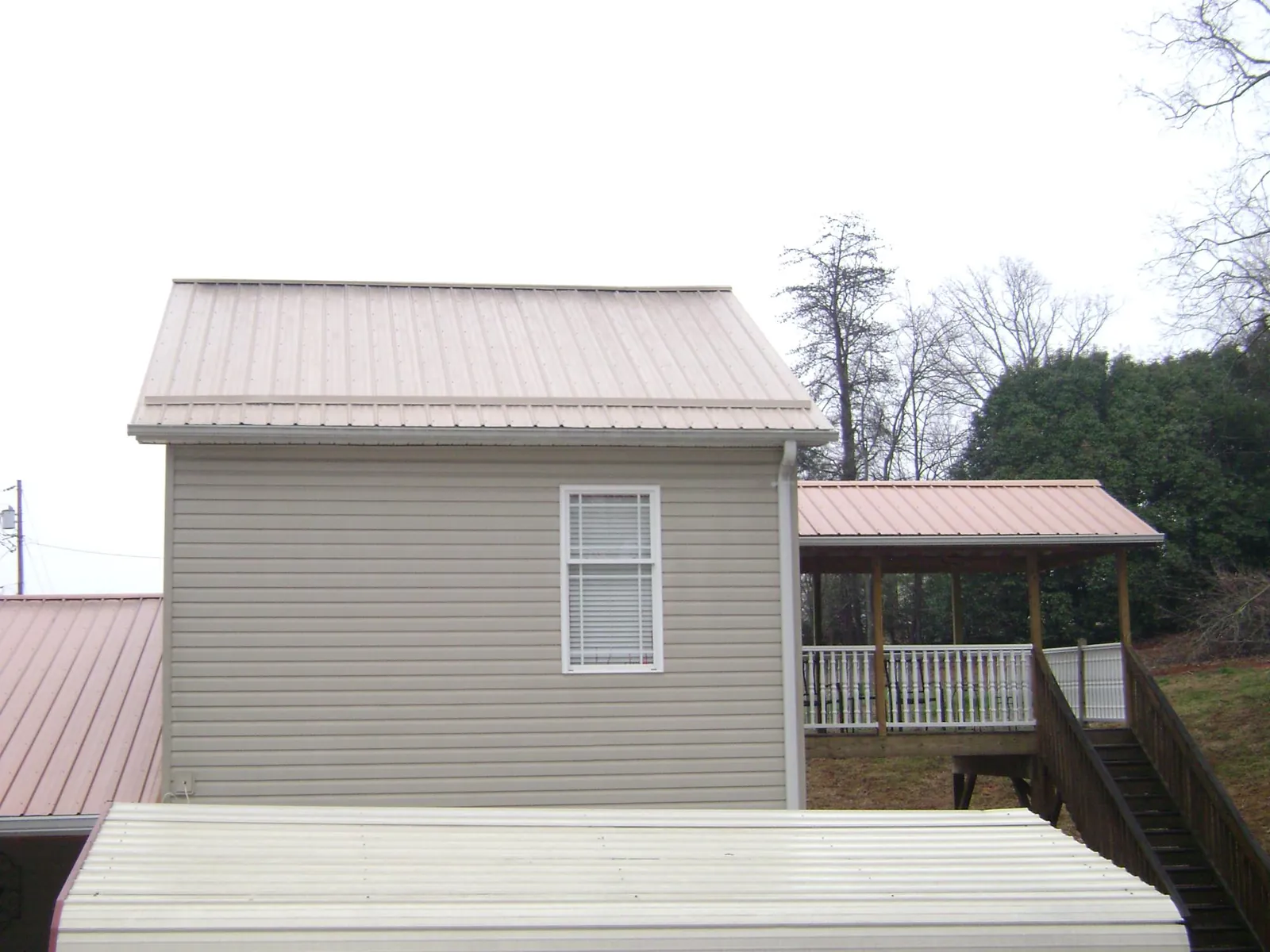 Tan metal roofs on a two story addition and attached porch, from a Roof Replacement job in Mays Landing