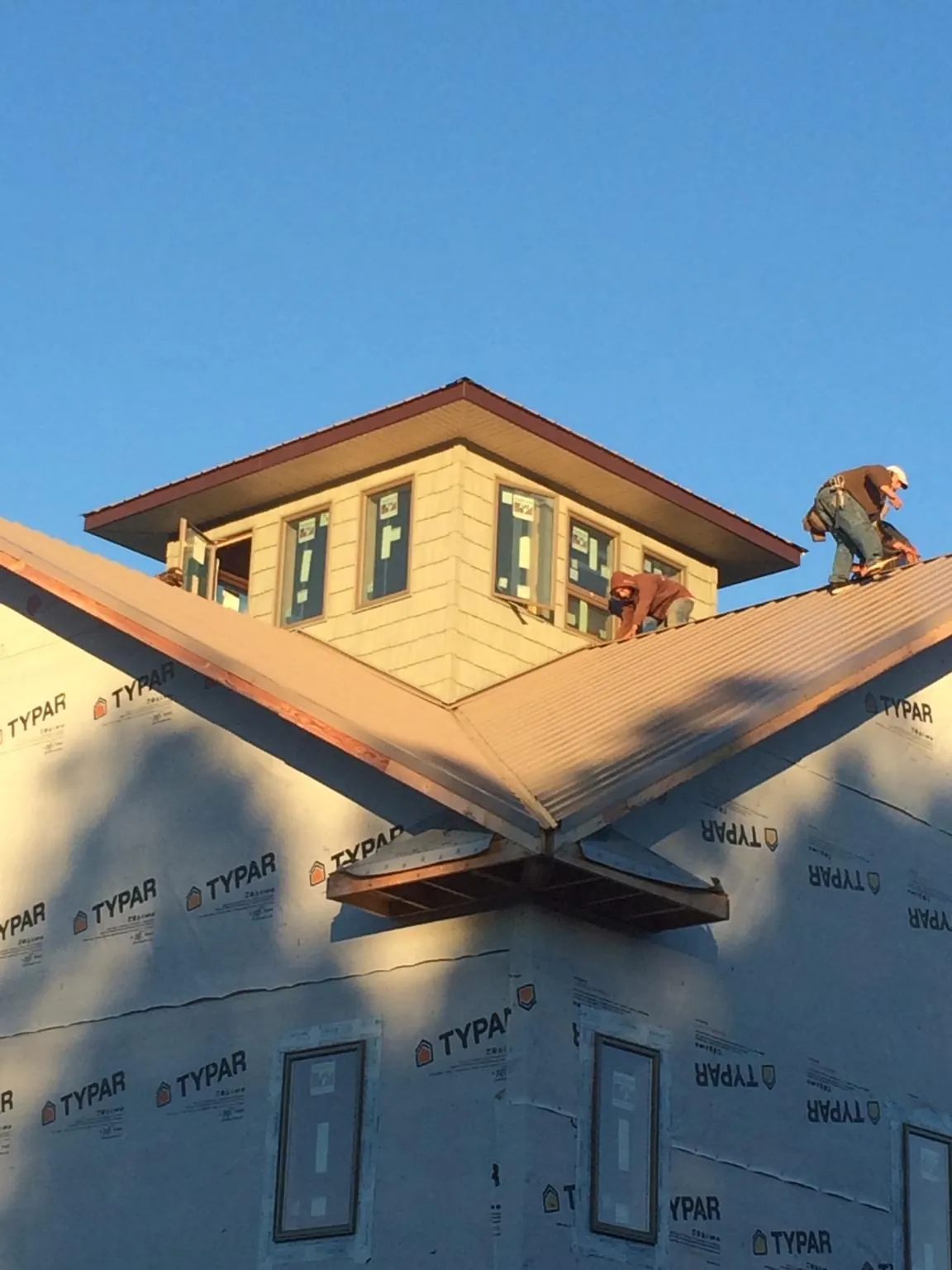 Roofers working around a rooftop cupola on a new metal roof at sunset — Roof Waterproofing in Mays Landing by Roofing Brothers